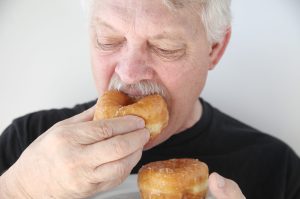 man biting into fresh doughnut